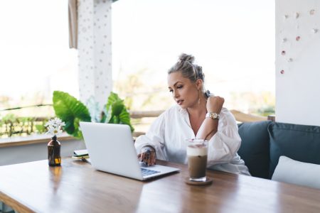 Beautiful Caucasian woman watching webinar video on modern netbook computer working remotely at terrace, millennial female IT professional reading received news on digital laptop technology